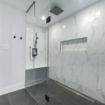 Modern bathroom with glass-enclosed shower and marble walls