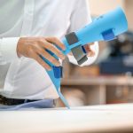 a man holding a blue hair dryer on top of a table
